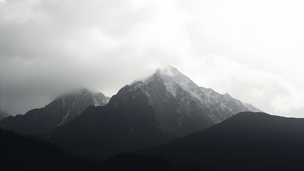 Black and white mountain range beneath a bright overcast white sky in daylight