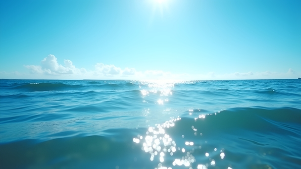 Bright daytime seascape with calm ocean waves and sunlight reflecting on the water surface
