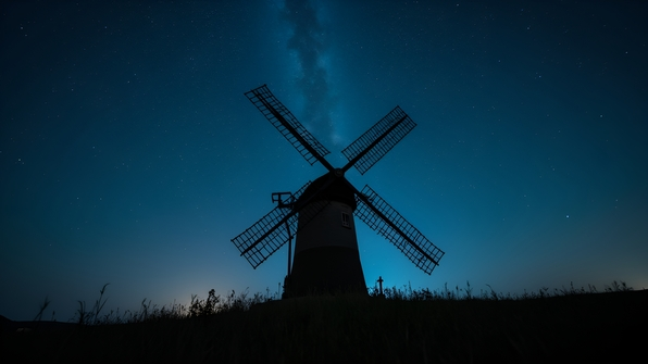 Silhouette of a classic windmill under a starry night sky with twinkling stars and a faint Milky Way