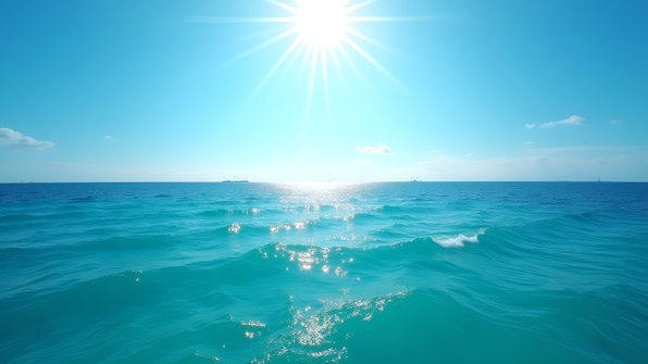 Clear blue ocean water sparkling under bright daytime sunlight with gentle waves and a vibrant, cloudless sky above