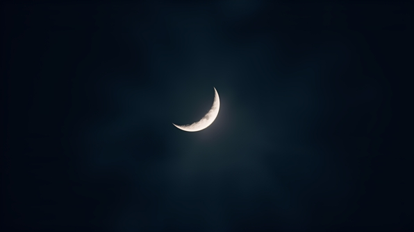 A crescent moon glowing softly in a dark, starless night sky with subtle atmospheric haze