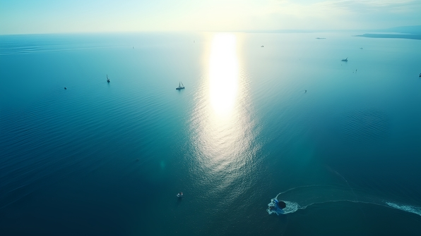 A vibrant aerial view of a deep blue ocean with gentle waves and sunlight reflecting on the water surface