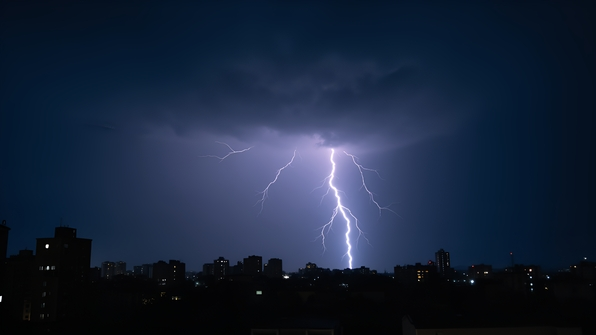 Lightning bolt striking over a silhouetted cityscape at night