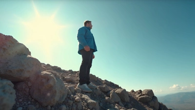 Man in Blue Jacket On Rocky Hill