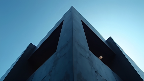 Modern black concrete building with sharp angles and minimalist design under a clear blue sky