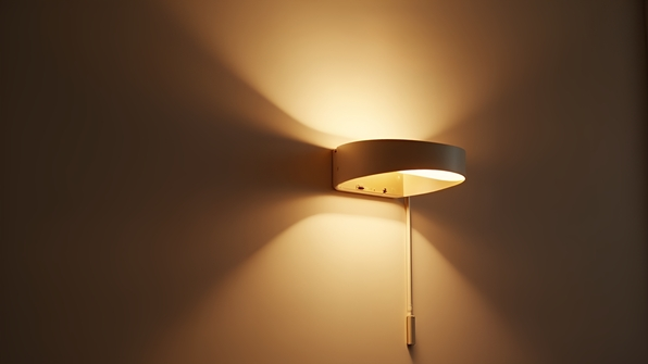A modern wall lamp emitting warm light on a neutral-colored wall in a minimalist interior