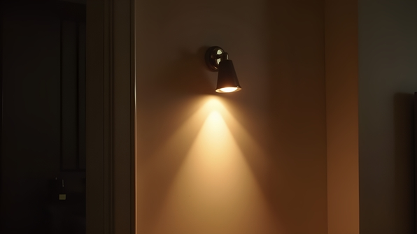 Modern wall-mounted light fixture emitting a warm glow on a textured interior wall in a cozy minimalist room