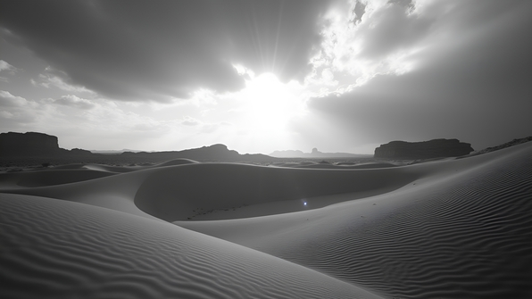 Monochrome landscape of rolling sand dunes under a cloudy sky highlighting texture and contrast