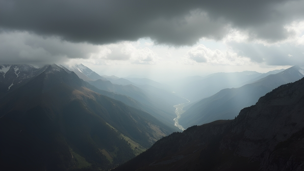 Aerial perspective of monochrome mountain range beneath overcast sky with dramatic clouds and rugged peaks