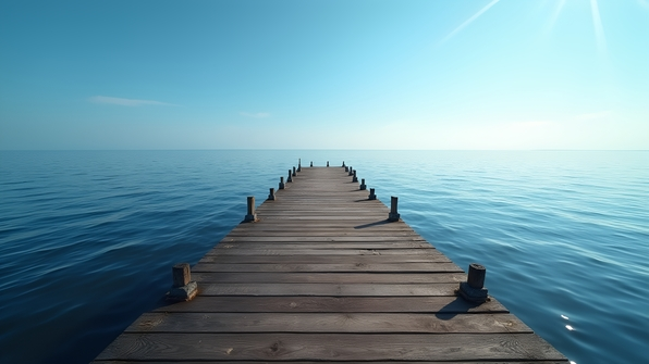 Rustic wooden dock extending over calm water with gentle ripples under clear blue sky