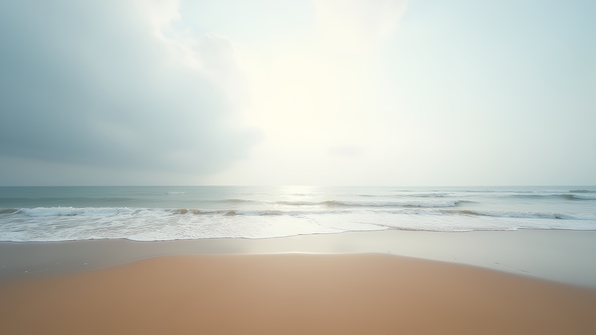 A serene sandy beach with gentle waves under an overcast white sky