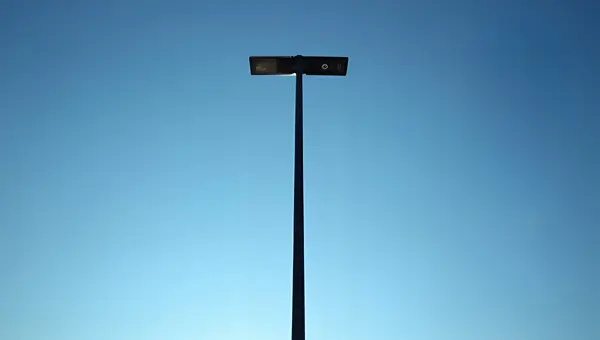 Tall Slender Black Metal Post Against Blue Sky