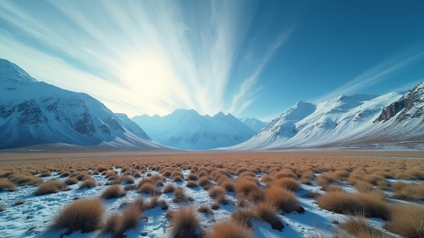 Vast tundra landscape with snow-covered mountains beneath a clear blue sky