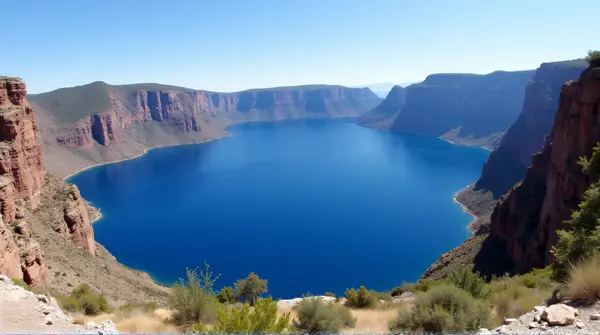 Deep blue alpine lake enclosed by towering rocky peaks and cliffs under a clear sky.