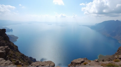 Blue Expanse Surrounded by Rugged Terrain Under Clouds