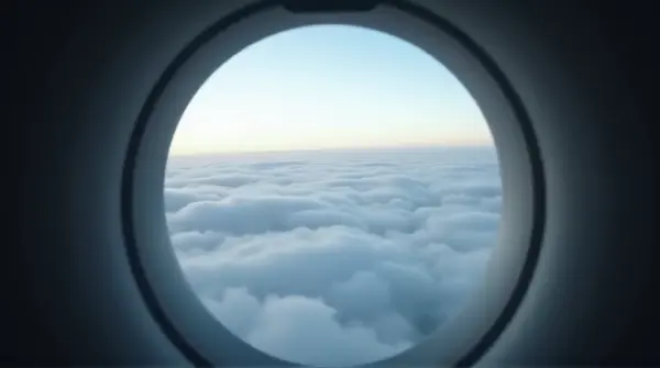 View through a circular aircraft porthole showing layered atmospheric horizons and soft gradients of light.
