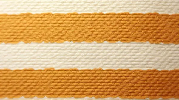 Close-up view of fabric with horizontal caramel and ivory bands under soft light
