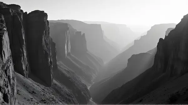Black and white panoramic view of craggy cliffs with sharp ridges and dramatic light contrast.
