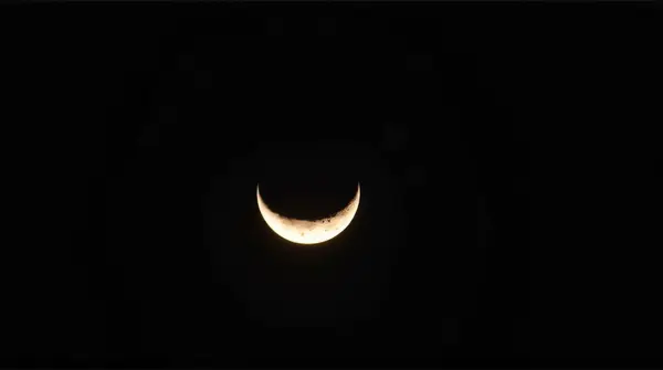 Close-up of a crescent-shaped planet showing detailed surface textures in dark space.
