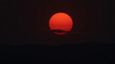Crimson Sun Rising Above Distant Hills At Dawn