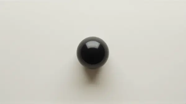 Top-down view of a dark orb resting on a pale surface showing smooth curvature.