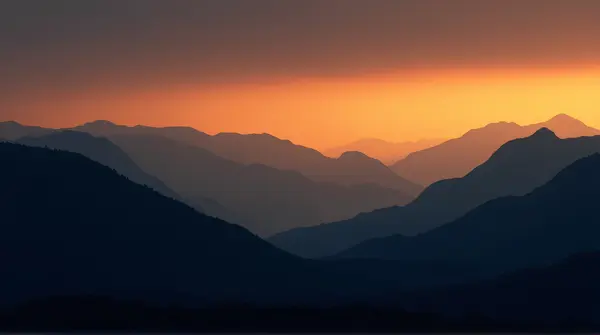 Dark ridges with sharp edges outlined against a glowing amber and deep blue sky, creating layered depth.