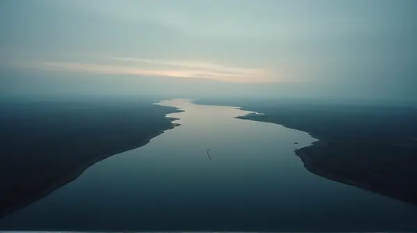 Dark water body bordered by faint shorelines under a dimming sky with horizon centered