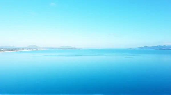 Wide lake with gentle ripples reflecting a bright sky and distant shoreline seen from above