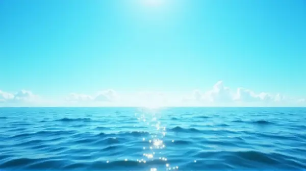 Wide ocean scene showing sunlight reflecting on gentle ripples beneath a clear sky from a low shoreline perspective.