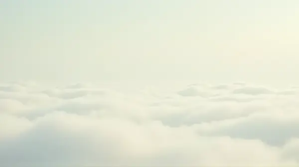 Wide pale sky covered by gentle vapor formations over a calm horizon under soft natural light.