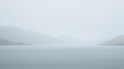 Foggy Water Expanses With Distant Hills Under Overcast Sky
