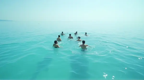 Group Swimming Across Clear Calm Water From Above