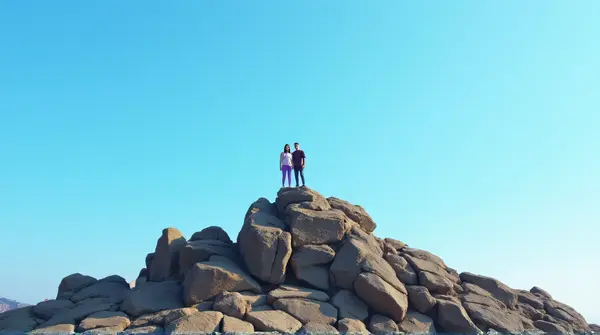 Hikers On Jagged Stone Outcrop Under Blue Sky