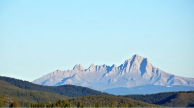 Jagged Peak Surrounded by Verdant Conifers and Hills