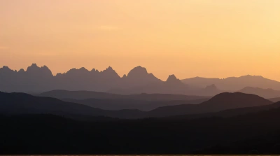 Jagged Peaks Silhouetted Against Amber Evening Sky