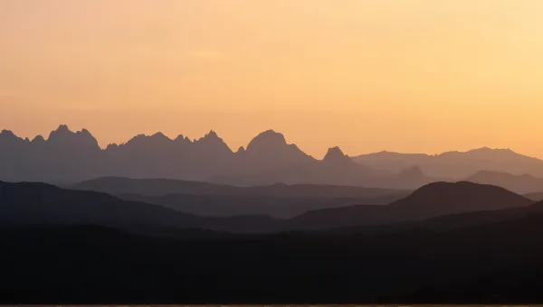 Jagged Peaks Silhouetted Against Amber Evening Sky