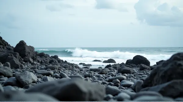 Low angle view of a jagged shoreline with stones and crashing surf under a wide open sky