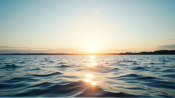 A large lake with gentle waves and warm sunlight under a clear sky stretching above the horizon.