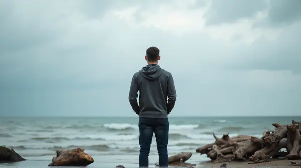 Man Contemplating Horizon Near Water Under Cloudy Sky