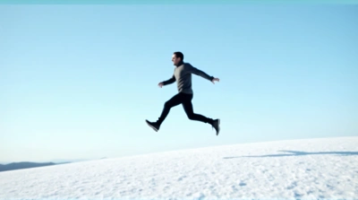 Man Leaping Across Frosty Field Under Clear Sky