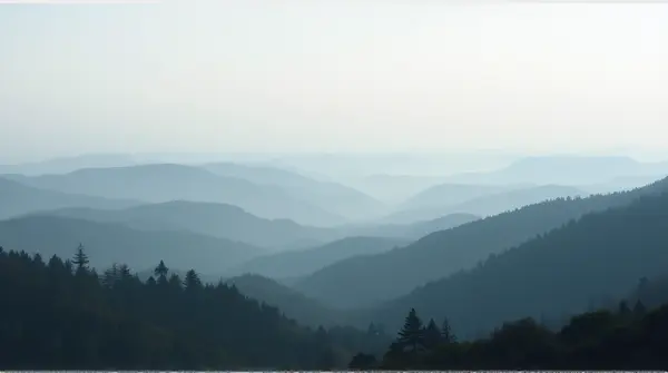 Panoramic view of undulating terrain covered in dense mist and layered textures fading into a muted horizon