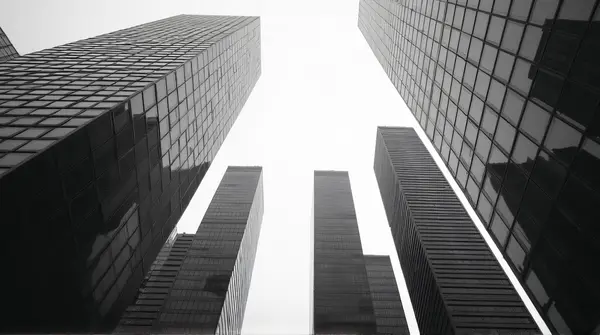 Black and white image of clustered tall towers showing geometric patterns and reflections from ground level