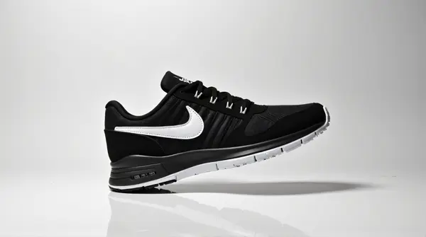 Monochrome black and white Nike athletic shoe angled on plain background showcasing stitching and branding.