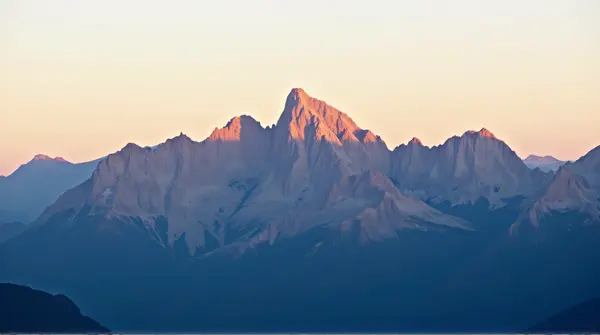 Rugged mountain peaks bathed in warm soft light under a clear sky at sunset.