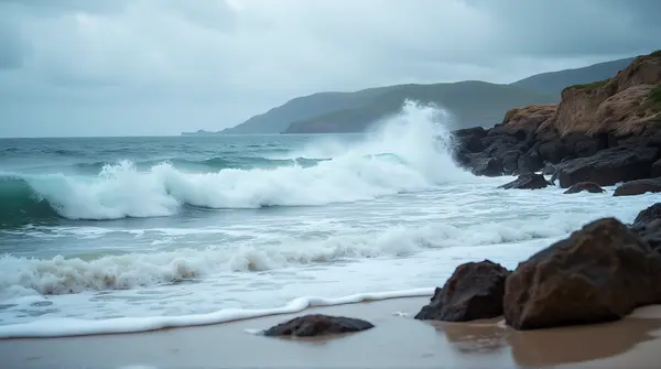 Dynamic ocean waves crashing into a rocky shoreline under a cloudy sky from a low angle perspective.