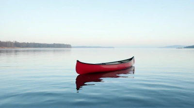 Red Canoe On Reflective Water With Tree Banks