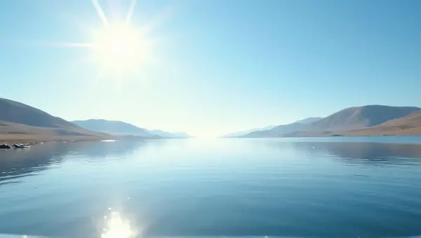 Reflective Water Surface Near Rolling Hills Under Sunlight