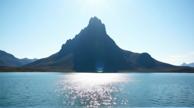 Rocky Peak Overlooking Shimmering Lake Under Clear Sky
