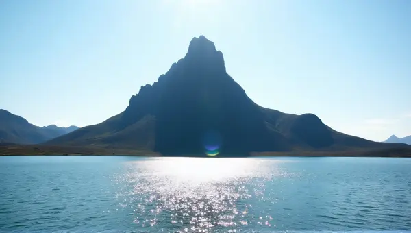 Rocky Peak Overlooking Shimmering Lake Under Clear Sky