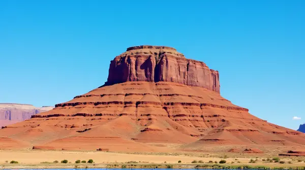 Low angle view of a rugged earth-toned peak with layered rocks against a clear blue sky